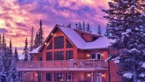 A log cabin with a balcony, surrounded by snow-covered trees. - The Lodge at Coliseum Mountain Resort (Clearwater County)