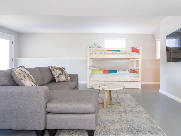 Una sala de estar moderna con un sofá gris, una cama litera y una pequeña mesa redonda.