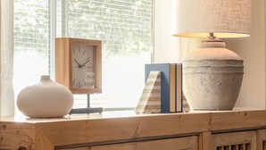 A wooden cabinet with a clock, books, and a lamp on a windowsill. - Bryant Creek Escape-Minutes from downtown (Walla Walla)