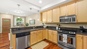 A modern kitchen with wooden cabinets, a granite countertop, stainless steel appliances, and a central island with a sink. - Bryant Creek Escape-Minutes from downtown (Walla Walla)