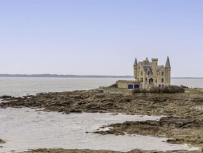 A castle-like building with a tower, situated on a rocky shoreline with a view of the sea. - Le Grand Large by Interhome (Quiberon)