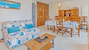 A living room with a sofa, wooden dining table, chairs, and a cabinet. - Le Grand Large by Interhome (Quiberon)