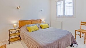 A bedroom with a bed, bedside tables, a chair, and a window. - Le Grand Large by Interhome (Quiberon)