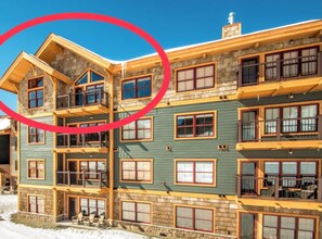 A multi-story lodge with a stone facade, wooden balconies, and a snow-covered ground. - SLOPESIDE Luxury Penthouse-Level Ski-In/Out Cranmore Mtn Condo!! (Conway)