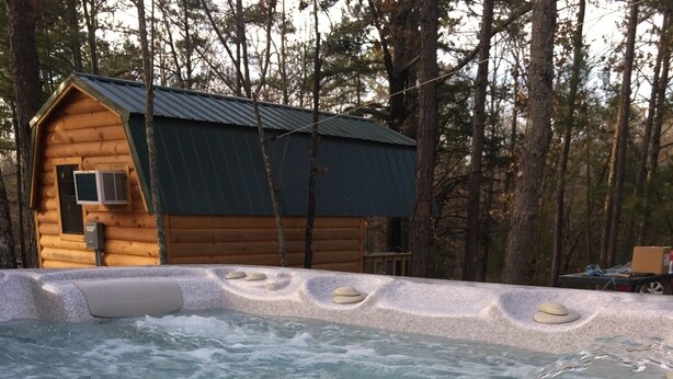 Ein Whirlpool mit einer Holzhütte im Hintergrund.