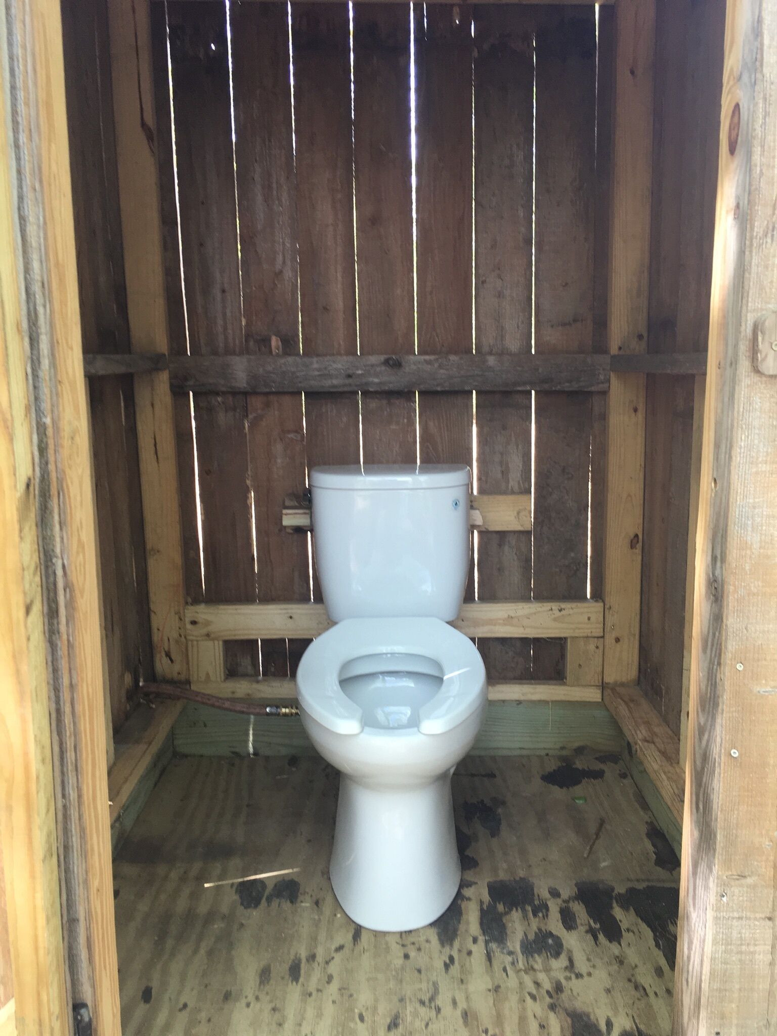 Une cabine de toilettes en bois avec des toilettes blanches.