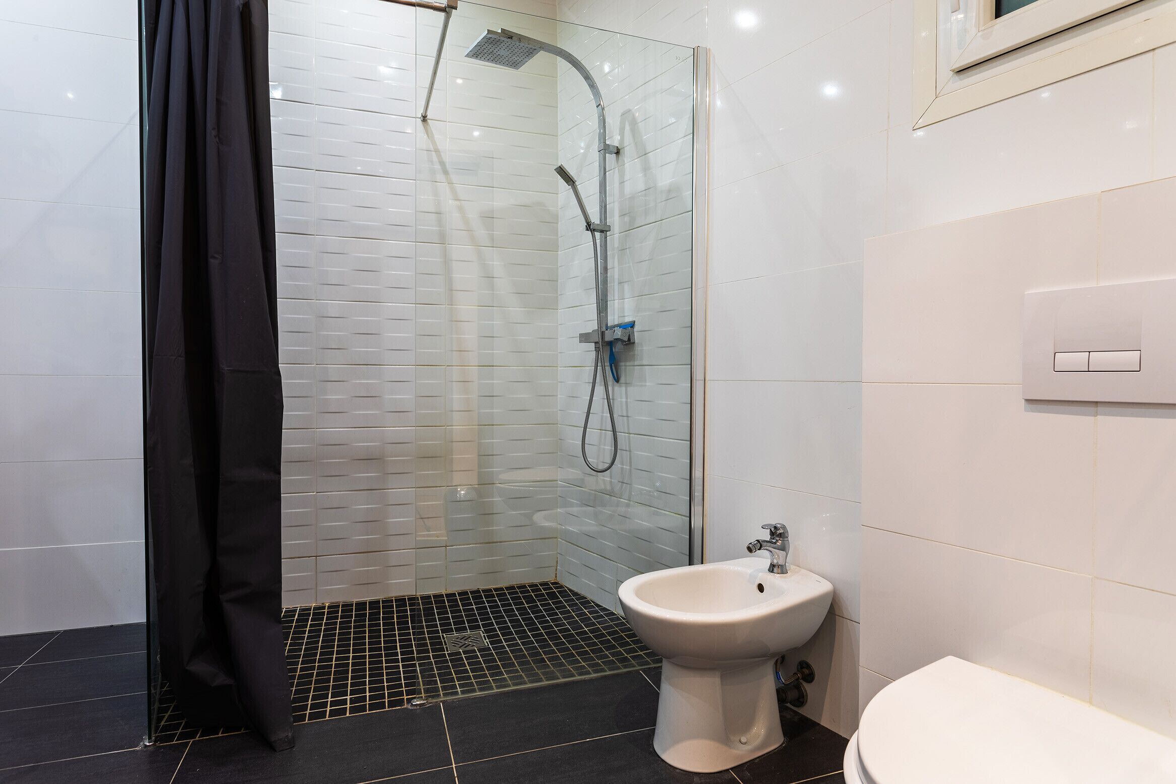 A modern bathroom with a glass shower enclosure, a white sink, and a toilet.