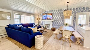 Ein modernes Wohnzimmer mit einem blauen Sofa, einem Holzessttisch und einem Kamin.