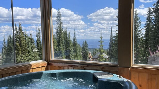 A hot tub with a view of a forest and mountains. - Ski in/ski out chalet. Mountain + valley views. Close to village. (Silver Star)
