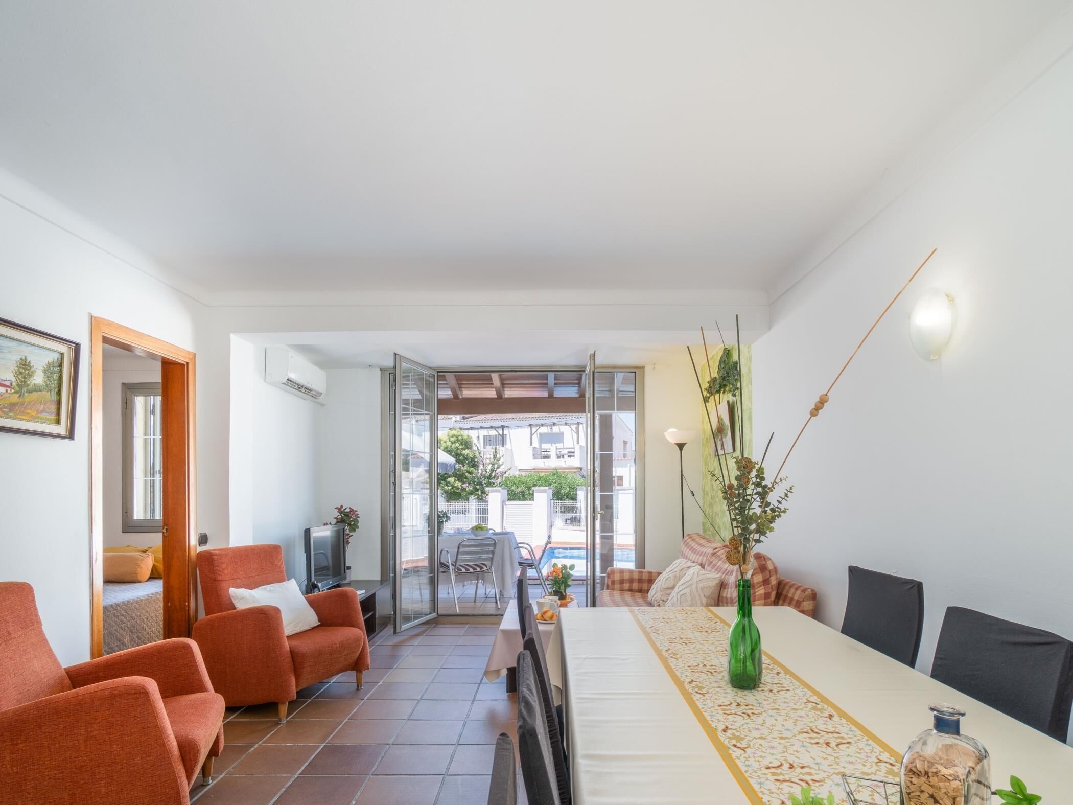 Una sala de estar con sofá, televisor y mesa de comedor con sillas.