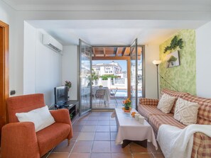A living room with a sofa, armchair, TV, and a table with a vase of flowers.