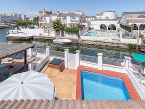 A waterfront property with a swimming pool, boats docked nearby, and Mediterranean-style architecture. - Casa de 4 habitaciones, 2 baños, piscina privada, amarre, wifi (Empuriabrava)