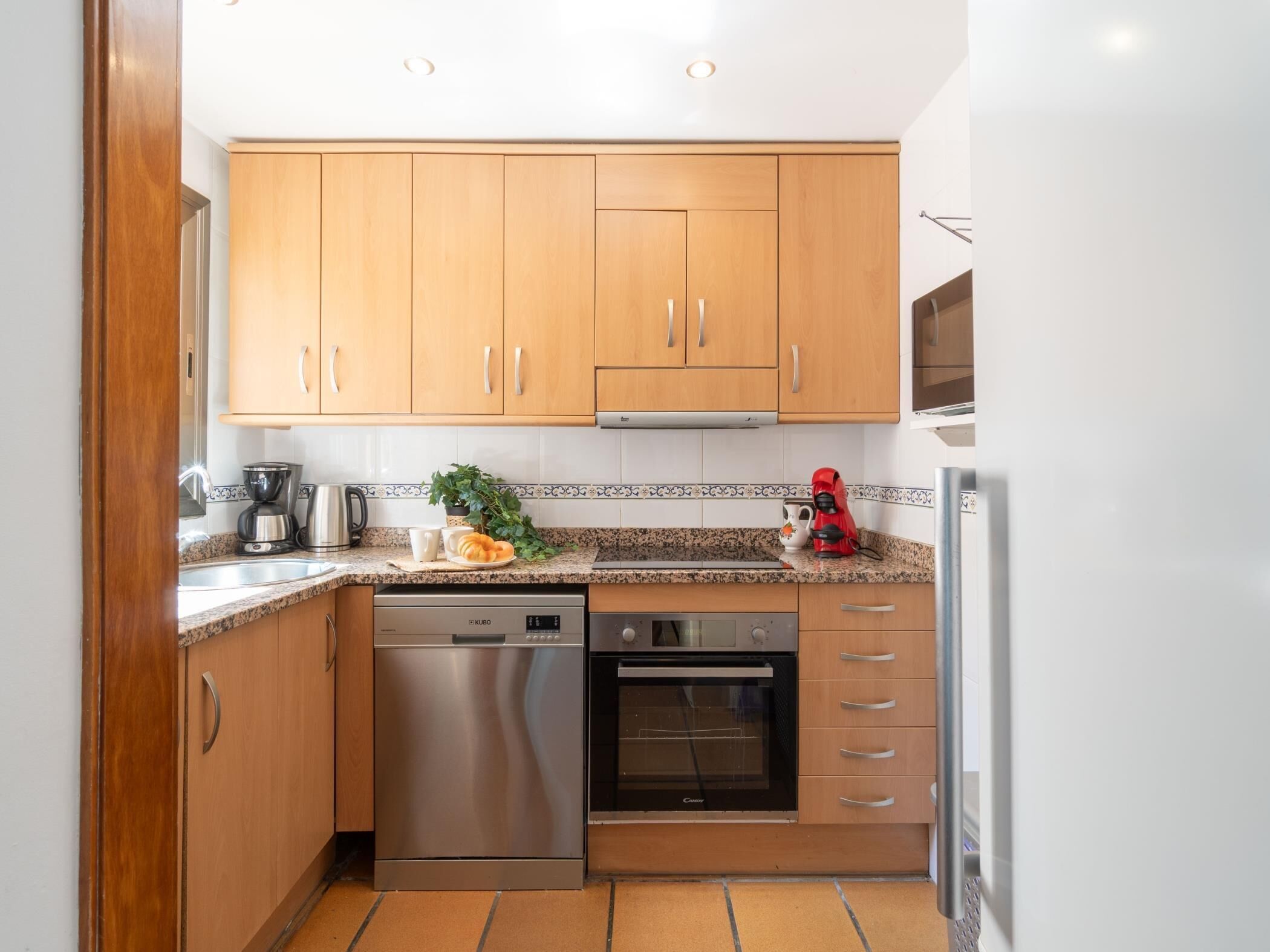 A compact kitchen with wooden cabinets, a dishwasher, an oven, and a refrigerator.