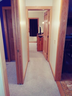 Enter a cozy room with a dark-colored door, flanked by wooden doors and a small table with a lamp.