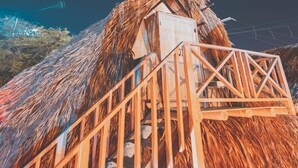 A thatched-roof structure with a wooden staircase leading to a small wooden building. - Kokohau Bungalows - Adults Only (Juan de Acosta)