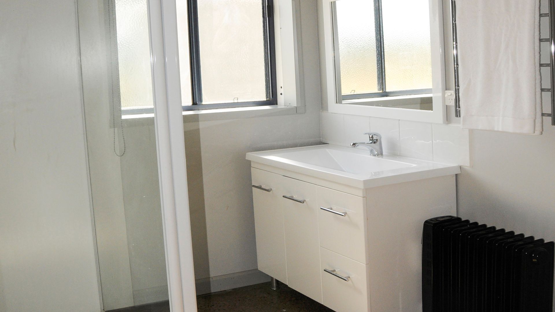 A bathroom with a white sink, a mirror, and a radiator.