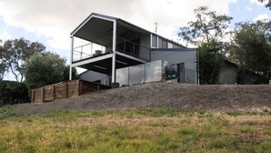 Une maison moderne à deux étages, dotée d’un toit plat et de grandes fenêtres.