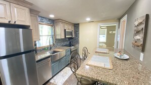 Cocina moderna con encimeras de granito, electrodomésticos de acero inoxidable y un comedor con mesa y sillas de granito.