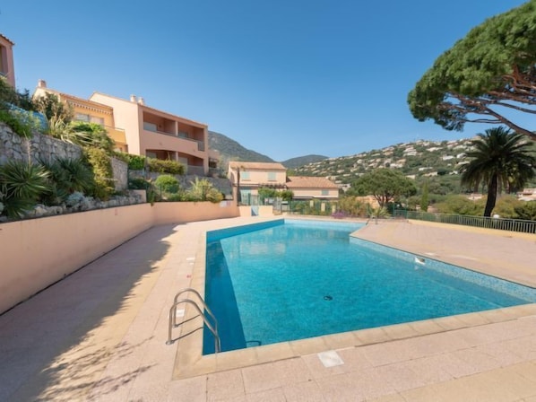 A rectangular swimming pool with a metal ladder, surrounded by a tiled deck.