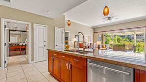 A modern kitchen with a large island, stainless steel appliances, and a view of a lush garden.