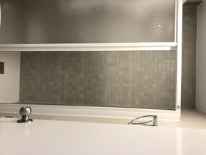 Relax in a serene bathroom with a large bathtub, walk-in shower, and geometric-patterned backsplash.