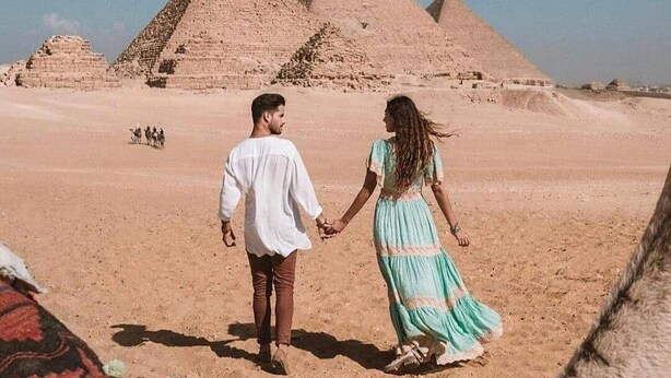 A couple walking on a desert with pyramids in the background. - Lovely 3-Bed Pyramids viewApartment in Kafr Nassar (Kafr Nassar)
