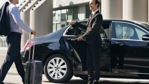 A black car with a man in a suit opening the door. - Lovely 3-Bed Pyramids viewApartment in Kafr Nassar (Kafr Nassar)