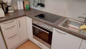 A compact kitchen with white cabinets, a built-in oven, a stovetop, and a sink. - Holiday apartment modern and appealing (Bad Mitterndorf)