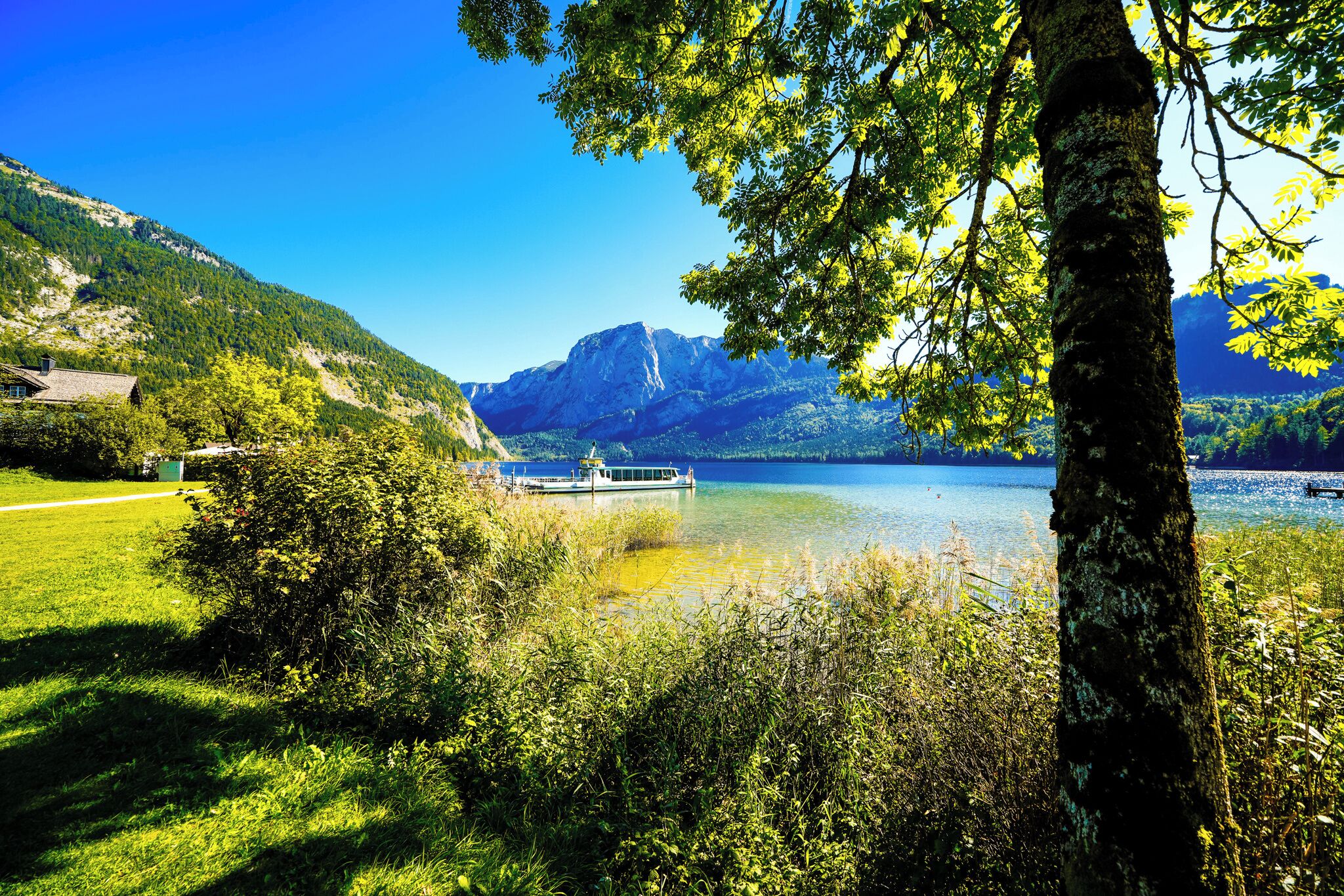Un lac avec un quai pour bateaux, entouré d’une végétation luxuriante et de montagnes.