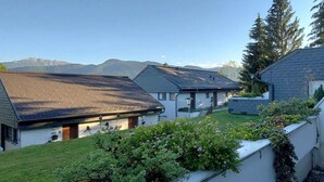 A residential area with houses, a grassy yard, and mountains in the background.
