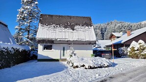 A snow-covered house with a chimney, a small window, and a door.