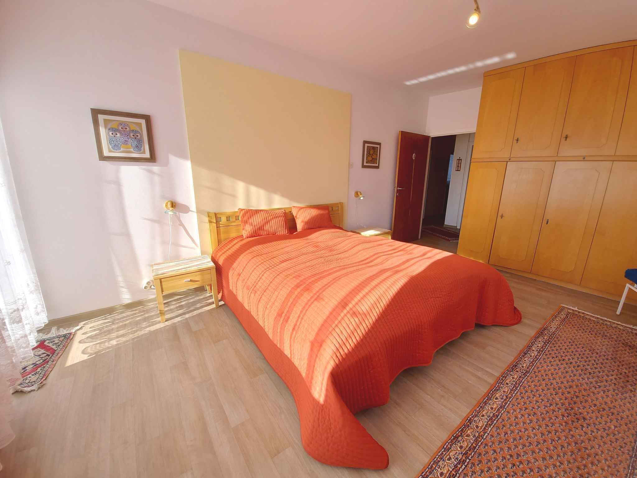 Una camera da letto con un letto di legno, un comodino, un armadio e un tappeto decorato.
