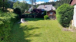 Ein gepflegter Garten mit Rasenfläche, einer Holzdiele und einem kleinen Schuppen.