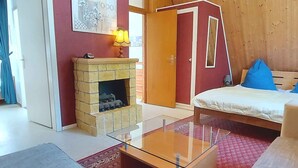Ein Schlafzimmer mit einem Bett, einem Glastisch, einem Kamin und einer Tür zu einem weiteren Raum.