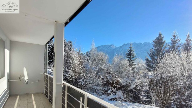 Un balcó amb vista a arbres i muntanyes cobertes de neu.