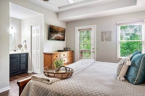 Quarto com cama, penteadeira, espelho, janela com persianas e porta.