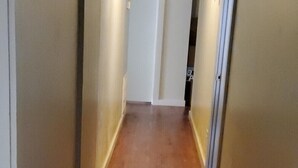 Un pasillo estrecho con suelo de madera y paredes blancas.