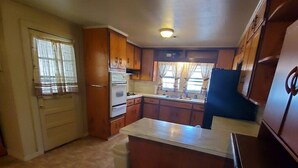 Una cocina compacta con armarios de madera, horno integrado y refrigerador.
