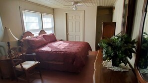 Un dormitorio con una cama grande, una silla, un escritorio y un espejo.