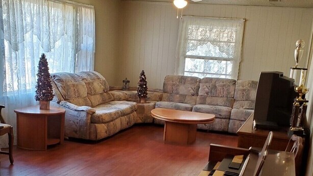 Una sala de estar con un piano, un sofá seccional, una mesa de centro y un televisor.