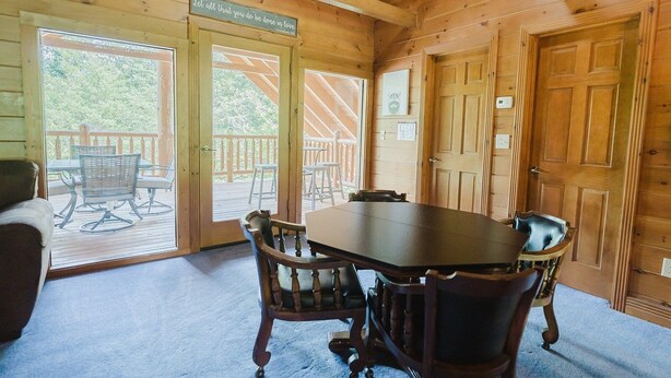 Une cabane en bois avec une table et des chaises, une terrasse en bois et une pancarte sur laquelle on peut lire : « Que tout ce que vous faites soit fait par amour. »