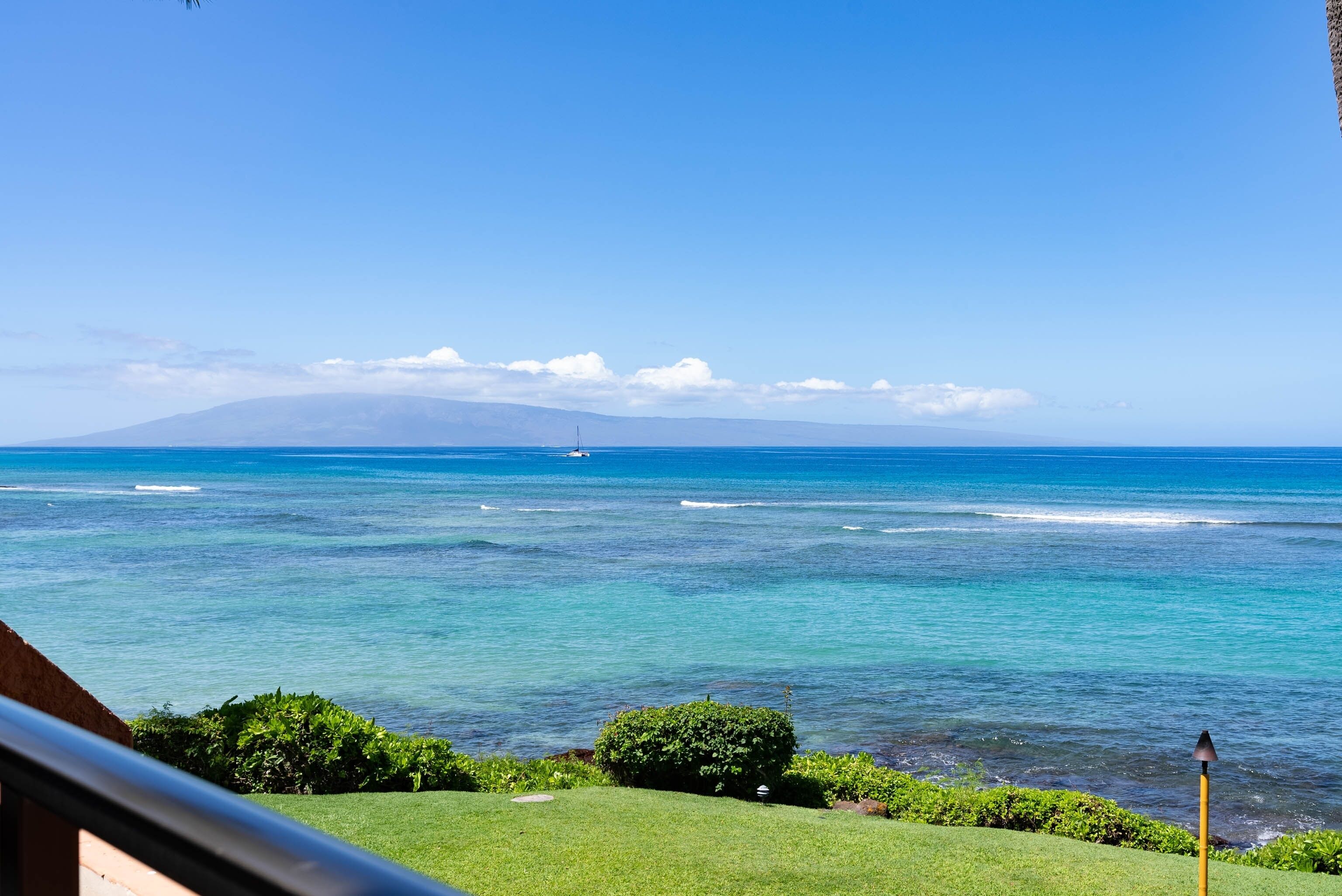 Une vue sur la côte, avec un ciel dégagé, des vagues sur l’océan et une montagne lointaine.