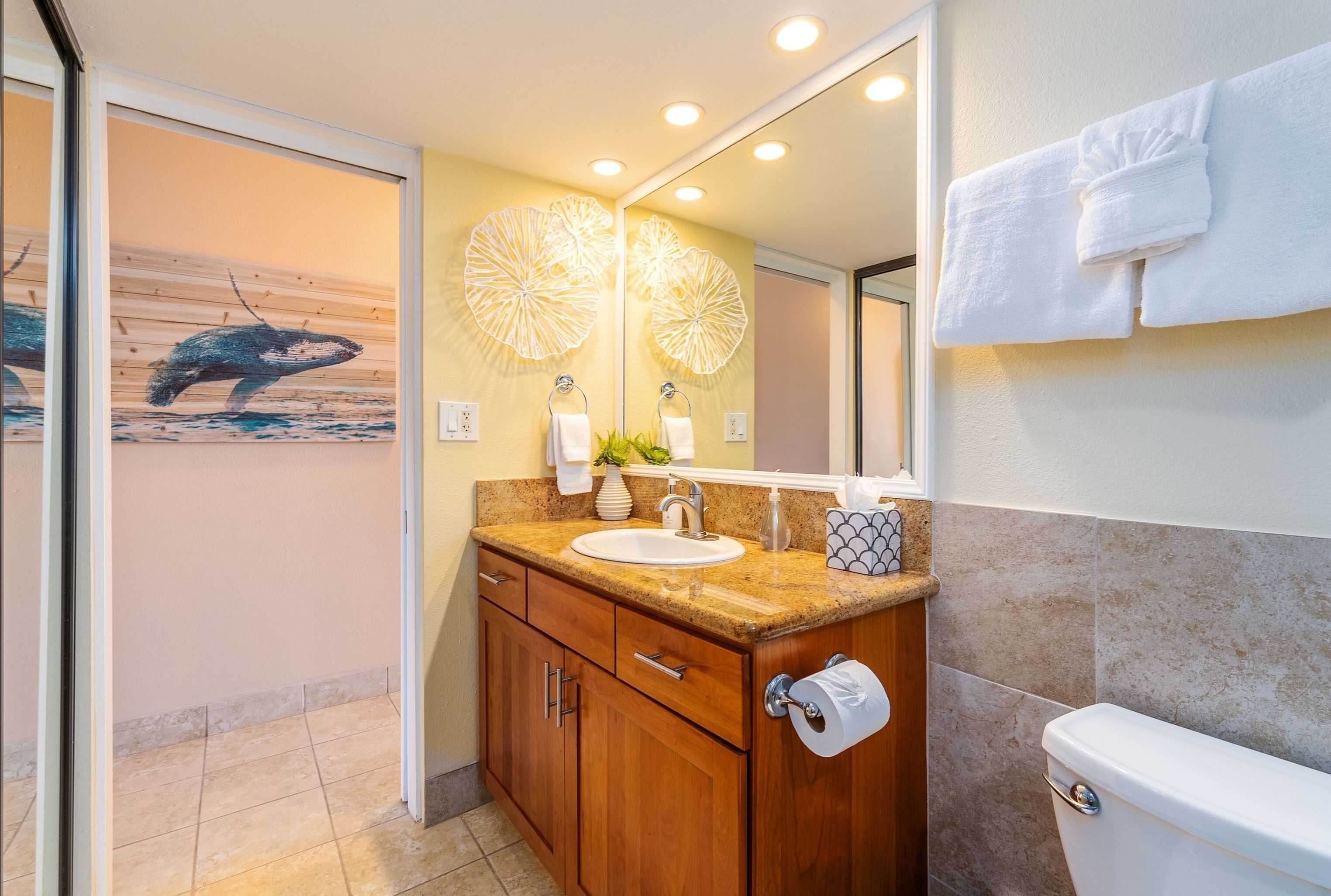 A modern bathroom with a wooden vanity, a sink, a toilet, and a large mirror.