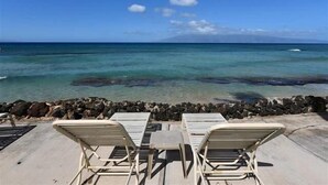 A beachside view with lounge chairs and a rocky shoreline. - Kaleialoha 209 1 Bedroom Condo by RedAwning (Lahaina)
