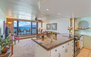 Una cocina moderna con una isla grande, un comedor con vista al océano y un balcón con vista al mar.