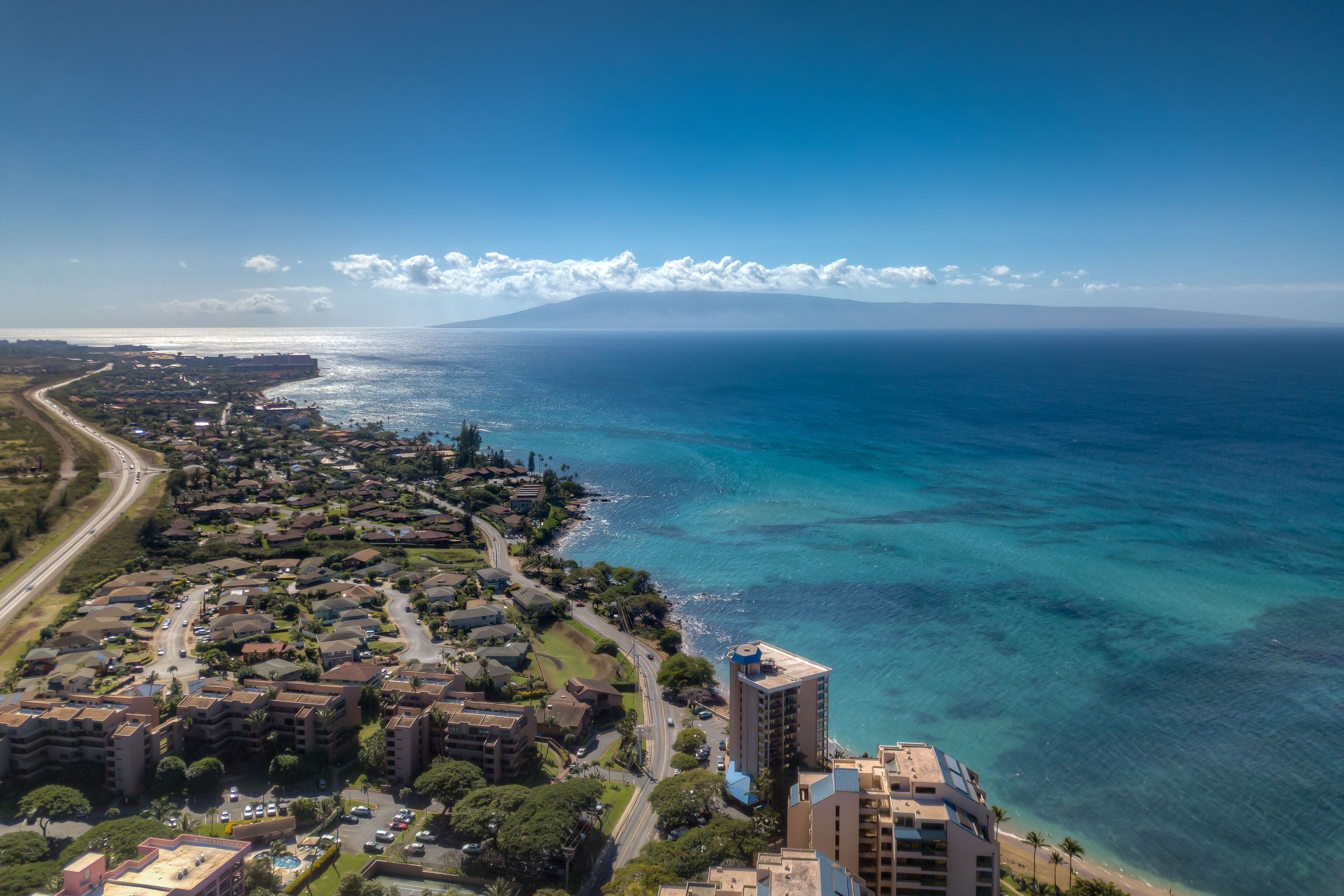 An aerial view of a coastal residential area with a prominent high-rise building near the beach.