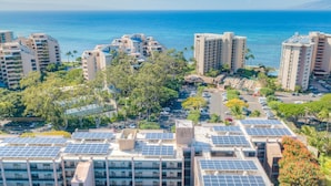 A high-rise hotel with multiple floors, rooftop solar panels, and a view of the ocean. - Kahana Manor 418 1 Bedroom Condo by RedAwning (Lahaina)