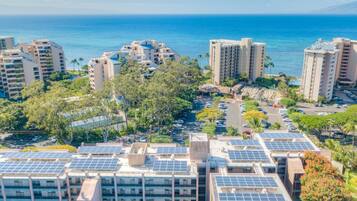 A high-rise hotel with multiple floors, rooftop solar panels, and a view of the ocean.
