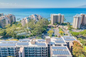 Un hotel de gran altura con varios pisos, paneles solares en la azotea y vista al océano.