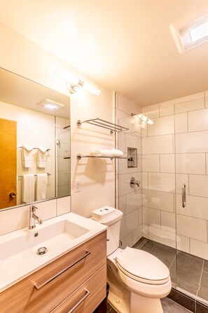 A modern bathroom with a white sink, vanity, and toilet. There is a glass shower enclosure and a mirror above the sink. - Modern 1 bedroom in Ski Trails by RedAwning (Truckee)